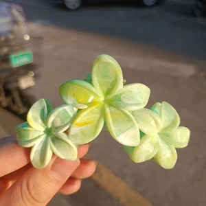 Detailed close-up of large green plumeria flower hair claw clip with matte marble texture