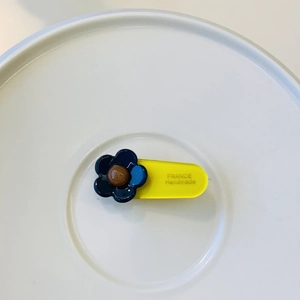 Detail of France Handmade logo engraved on a yellow acrylic floral hair clip