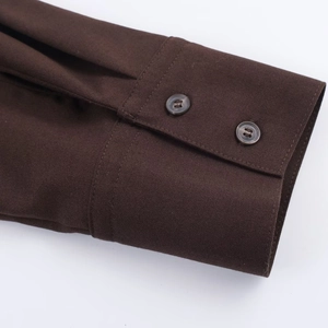 Close-up of deep brown shirt cuff showing fine plain weave fabric and resin buttons