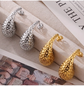 Détail macro de boucles d'oreilles goutte avec texture martelée en doré et argenté
