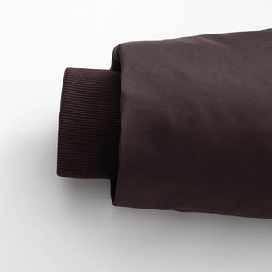 Close-up of deep brown hooded jacket showing ribbed knit cuffs and plain weave fabric texture