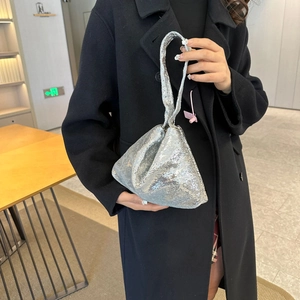 Sac à main triangle à paillettes argentées avec bandoulière torsadée porté par un mannequin