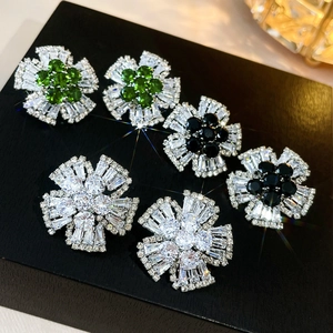 Détail macro de boucles d'oreilles fleurs avec pierres de zircone vertes, noires et claires