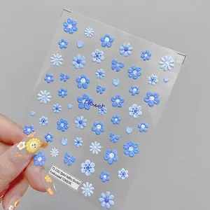Macro detail of 3D embossed nail stickers with blue floral heart and ribbon designs
