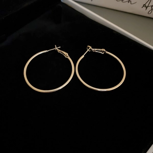 Detailed view of gold hoop earrings with metallic luster on black velvet lining
