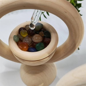 Close-up of glass dropper adding essential oil to natural agate stones in a wooden diffuser