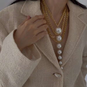 Detail of multi-layer gold chain necklace with cascading white pearls on a model