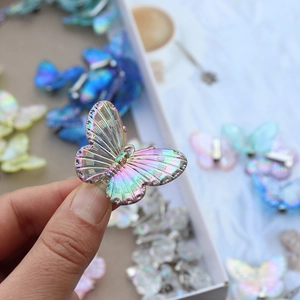 Hand holding a dreamy gradient butterfly hair clip with colorful holographic laser finish
