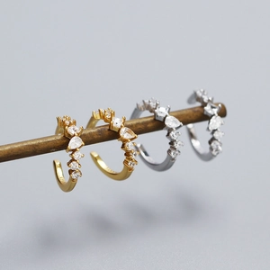 Macro shot of U-shaped gold and silver ear cuffs featuring sparkling cubic zirconia stones