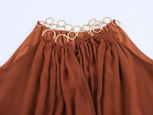 Detailaufnahme des goldenen Metallring-Dekolletés am ärmellosen Terrakotta-Chiffonkleid