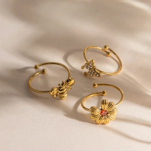 Détail macro du lot de bagues dorées 18K avec motifs abeille, papillon et marguerite