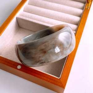 Detail eines breiten Harzarmreifs mit Rauchmuster in einer hölzernen Schmuckbox