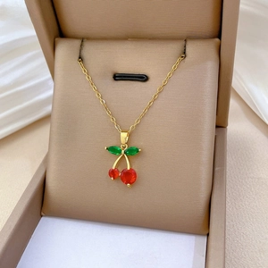 Detailed close-up of cherry pendant with red and green zircons on gold chain