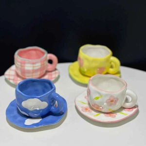 Flat lay of four sets of hand-painted ceramic coffee cups with floral and grid patterns