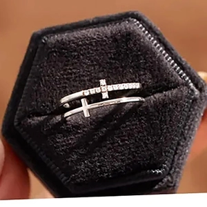 Detail view of silver double-layered cross ring with crystals in black velvet box