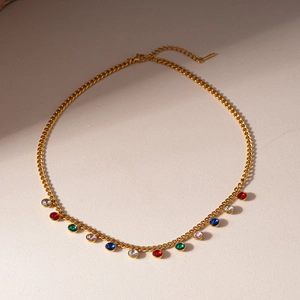 Close-up of golden sweater chain featuring colorful teardrop and round cubic zirconia stones