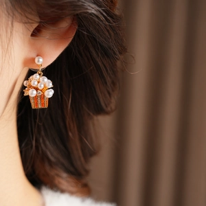 Close-up of popcorn bucket earrings with white pearls and sparkling cubic zirconia stones