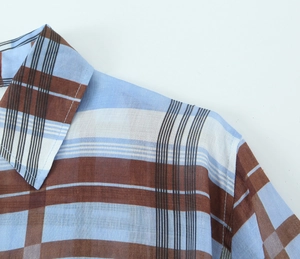 Detailed macro view of the ramie fabric texture and stitching on blue plaid dress shirt