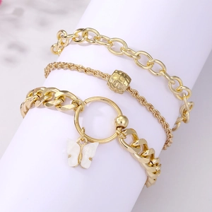 Dreiteiliges goldenes Armband-Set mit weißem Schmetterlingsanhänger auf einem Display