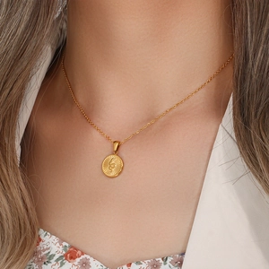 Detailed close-up of a gold necklace with a snake pattern on a round pendant for women