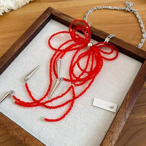 Macro shot of red beaded bow necklace with silver tassels on a white display tray