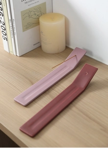 Detalle de portainciensos minimalistas en cerámica rosa y terracota sobre madera