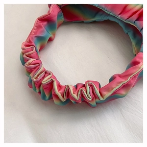 Close-up of rainbow gradient pleated satin fabric with silky texture and elastic texture