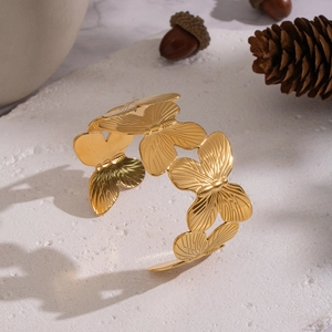 Exaggerated wide butterfly gold plated open bangle on elegant stone background