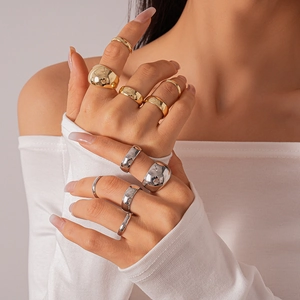 Close-up of stacked geometric metal rings in gold and silver finish on model's hand