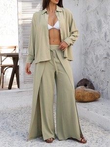 Detail of high-waisted wide-leg trousers with side slits and a matching relaxed linen shirt
