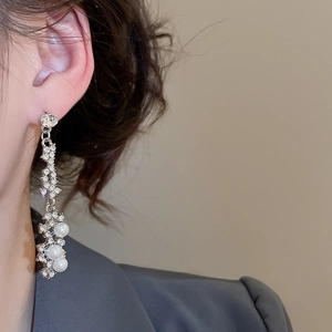 Detail of silver drop earrings with sparkling rhinestones and white pearls on a model