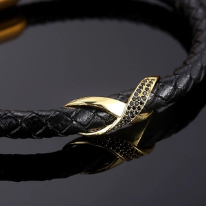 Detail of black woven leather bracelet with gold infinity buckle and black rhinestones