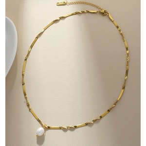 Detail view of a gold snake chain necklace featuring a white baroque pearl pendant