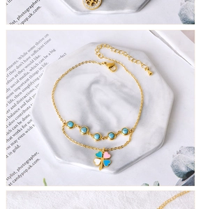 Detail of double-layer gold anklet with turquoise beads and colorful clover pendant