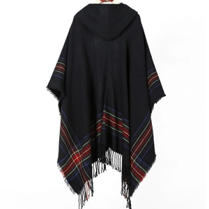 Detailed close-up of the black plaid hooded poncho featuring soft fringe tassels on the edge