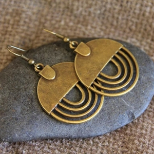 Ethno-Ohrringe aus Bronze mit geometrischem Hohl-Design auf Kieselsteinen und Sackleinen
