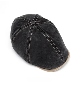 Top view of dark grey washed denim beret featuring white stitching and button detail