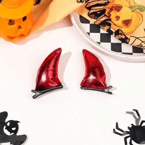 Detailed view of red devil horn hair clips with glossy finish on Halloween backdrop