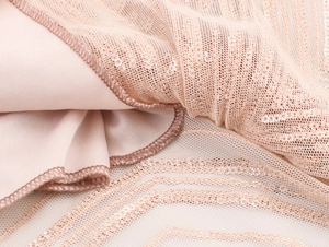Détail du tissu à paillettes champagne et mesh élégant sur la robe de soirée de luxe