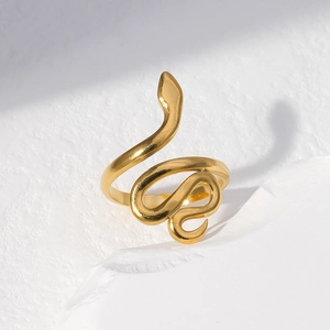 Detailed view of the golden snake-shaped ring on a textured white background with light shadows