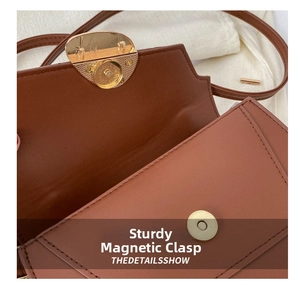 Detail shot of golden magnetic buckle on smooth brown leather shoulder bag for women