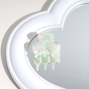 Detail of mint green marble acetate hair claw clip on heart-shaped mirror surface