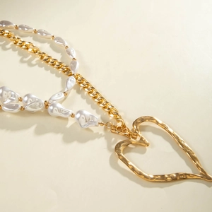Close-up of golden multi-layer necklace with irregular white pearls and heart pendant