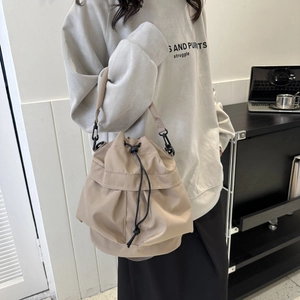 Détail du sac seau beige en nylon satiné avec cordon de serrage et crochets noirs