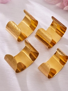 Vue détaillée de quatre ronds de serviette plaqués or avec des textures de métal uniques