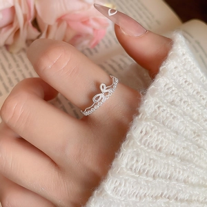 Close-up of elegant silver bow ring with zircon pavé worn with a knit sweater