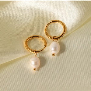 Detail of gold hoop earrings with baroque freshwater pearls on silk background