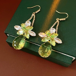 Detailed view of flower zirconia earrings with green water-drop pendants on leather