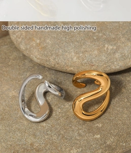 Macro shot of gold and silver polished metal ear cuffs resting on natural stone texture