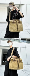 Detail of large canvas messenger bag featuring reinforced leather handles and dual front pockets